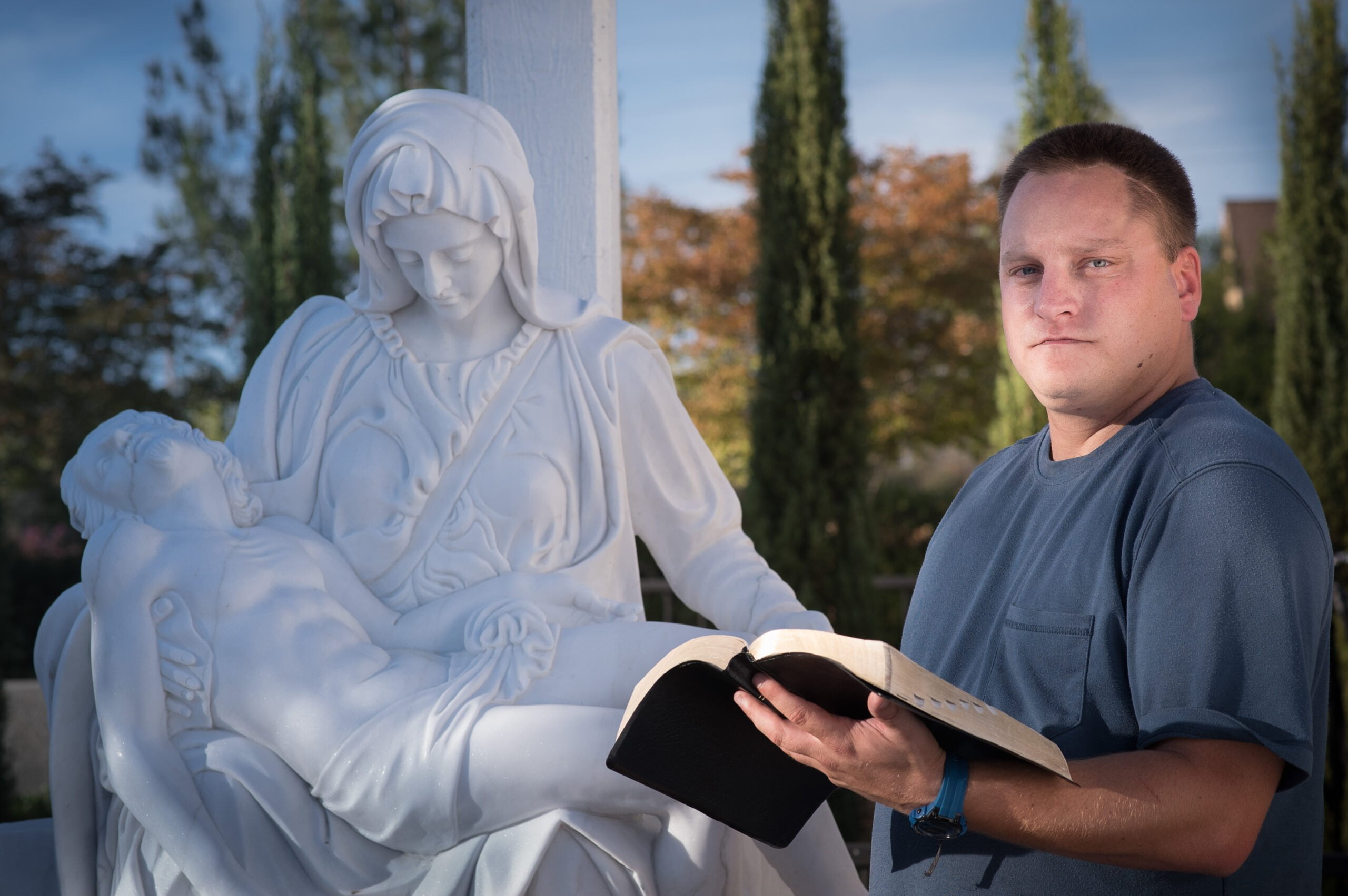 Matthew Sprenger by a statue at his church.